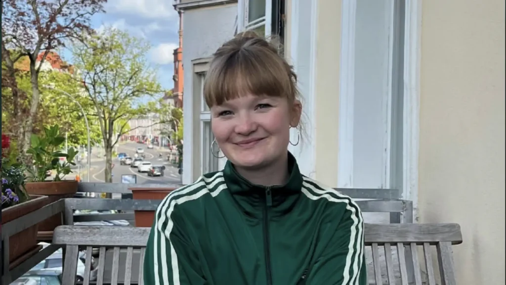 Helen Blaschke sitzt auf einem Balkon und lächelt in die Kamera